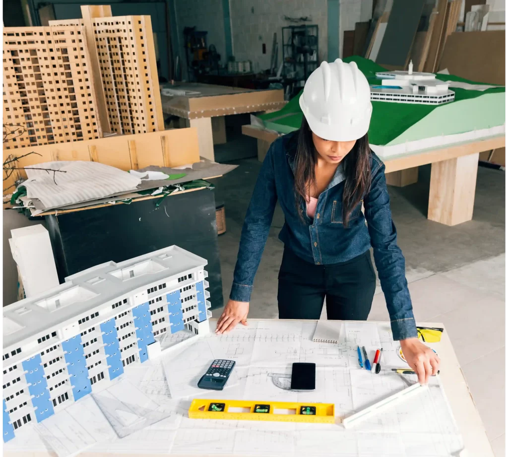 Lady drawing a plan standing near the model of a building