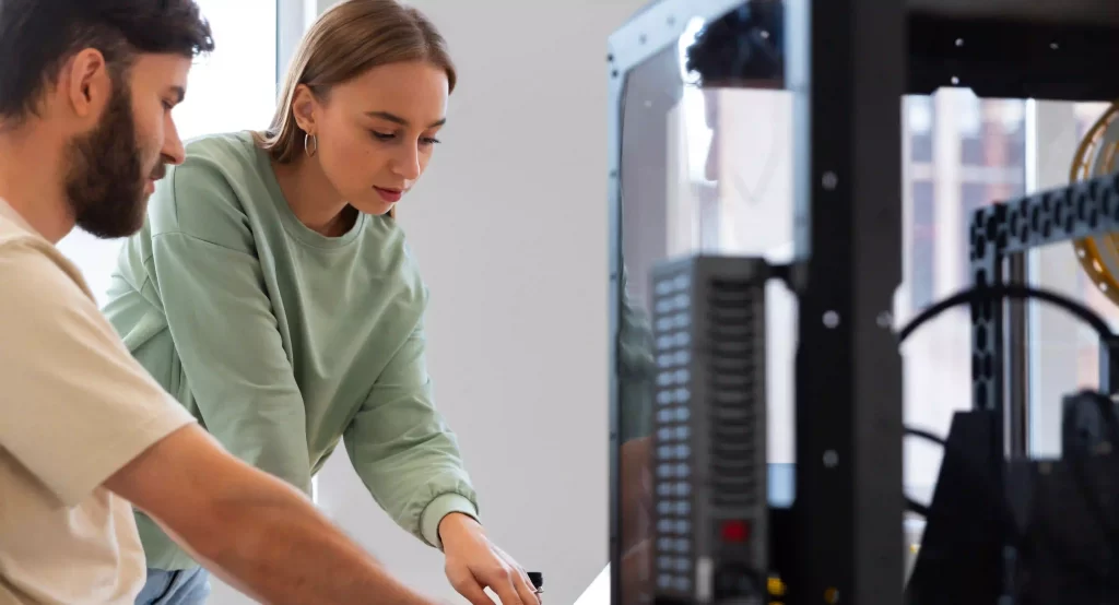 2 people discussing near a 3d printer