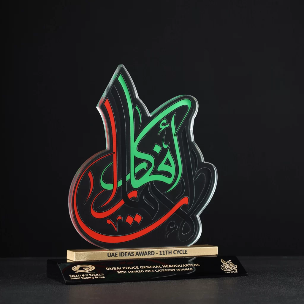 Custom calligraphy-shaped crystal award with black base, engraved for Dubai Ideas Award by Dubai Quality Group, showcasing personalized crystal and glass trophies.