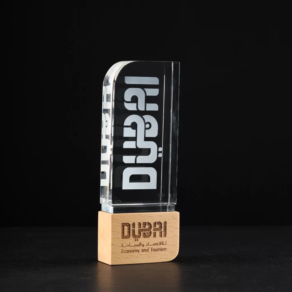 Custom crystal trophy with wooden base featuring iconic “Dubai” tourism logo text, crafted for Dubai Economy and Tourism.